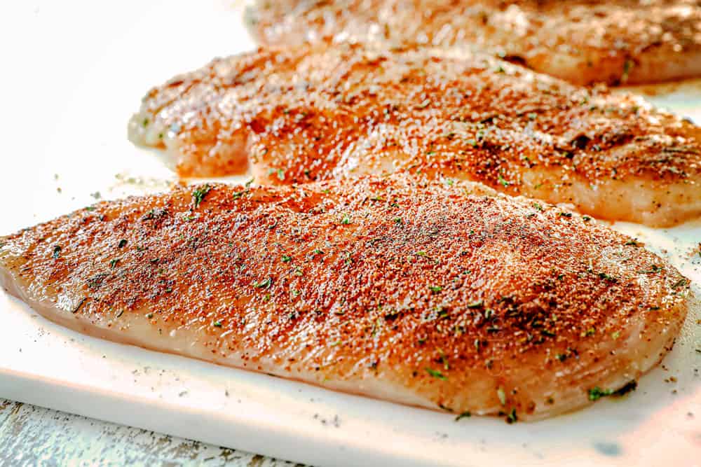 showing how to make jerk chicken pasta recipe (Rasta Pasta) by seasoning chicken with jerk seasoning