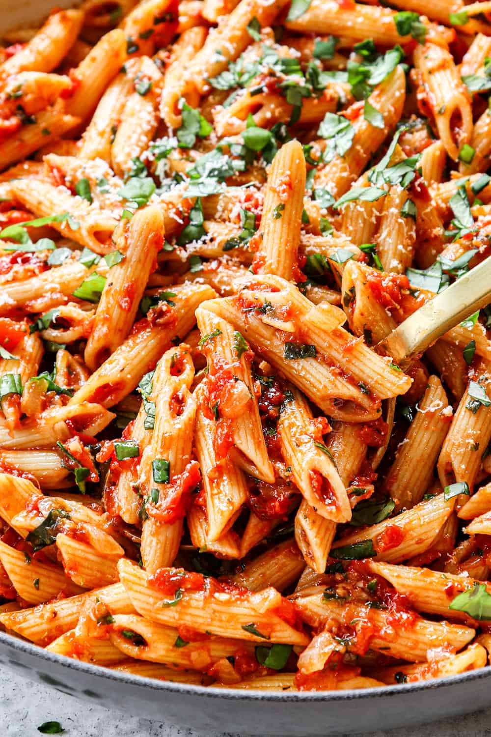 up close of scooping up penne arrabbiata garnished by Parmesan cheese