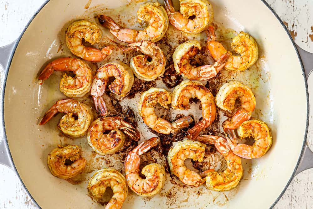 showing how to make coconut shrimp curry recipe by sautéing shrimp in a pan with oil