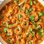 top view of cooking curry shrimp in a pan garnished with cilantro