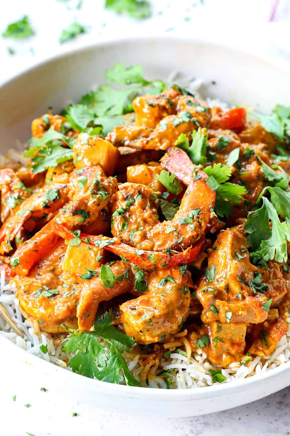 serving curry shrimp over rice garnished by cilantro