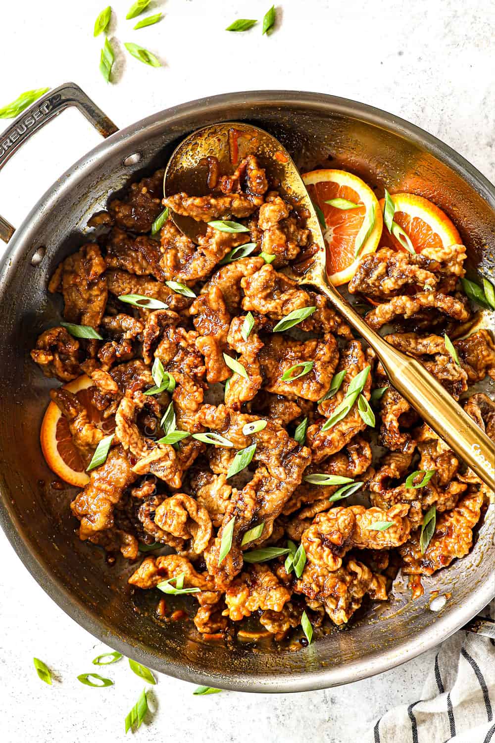 top view of making orange beef by garnishing with green onions and sesame seeds