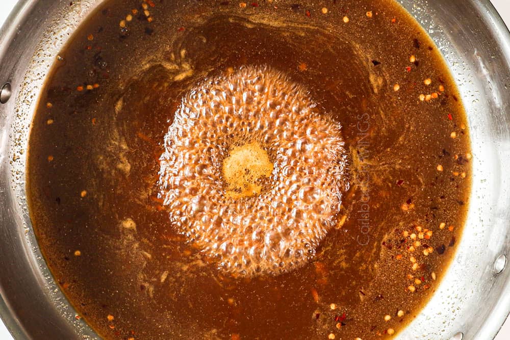 top view showing how to make orange beef recipe by o simmering orange sauce in a sauce pan