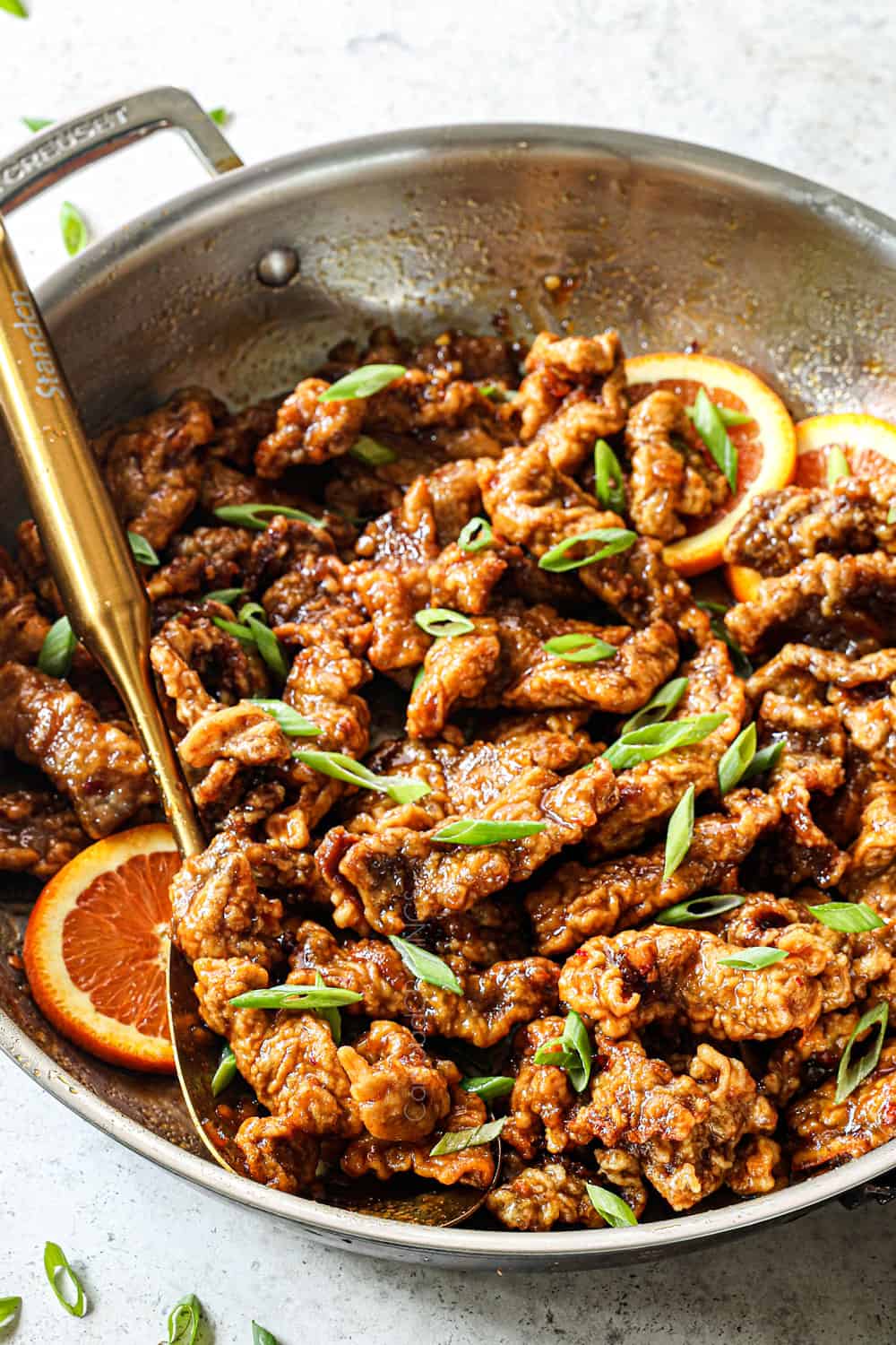 combining orange beef and orange sauce in a stainless steel saucepan