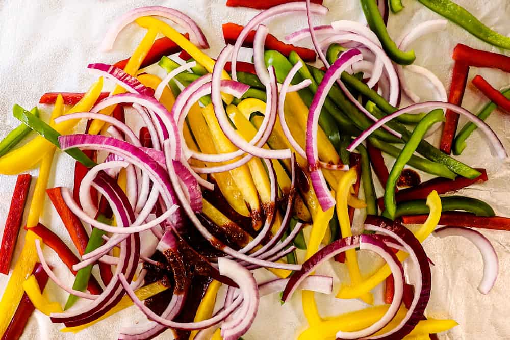 showing how to make sheet pan chicken fajitas by tossing bell peppers and red onions with fajita marinade