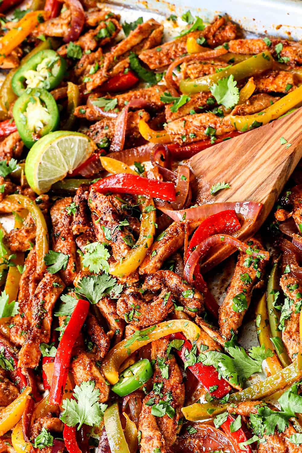 up close of serving sheet pan chicken fajitas by scooping up the chicken and vegetables