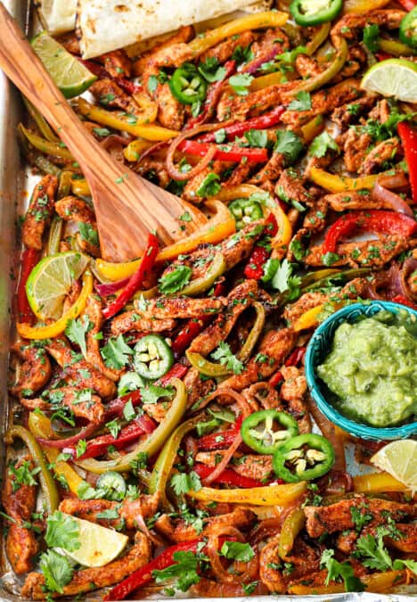 up close of scooping up sheet pan chicken fajitas to serve in flour tortillas
