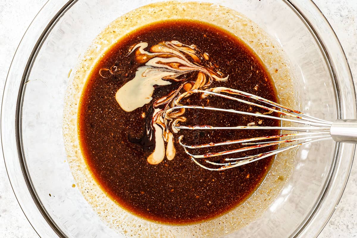 showing how to make udon noodles by whisking together the stir fry sauce in a bowl