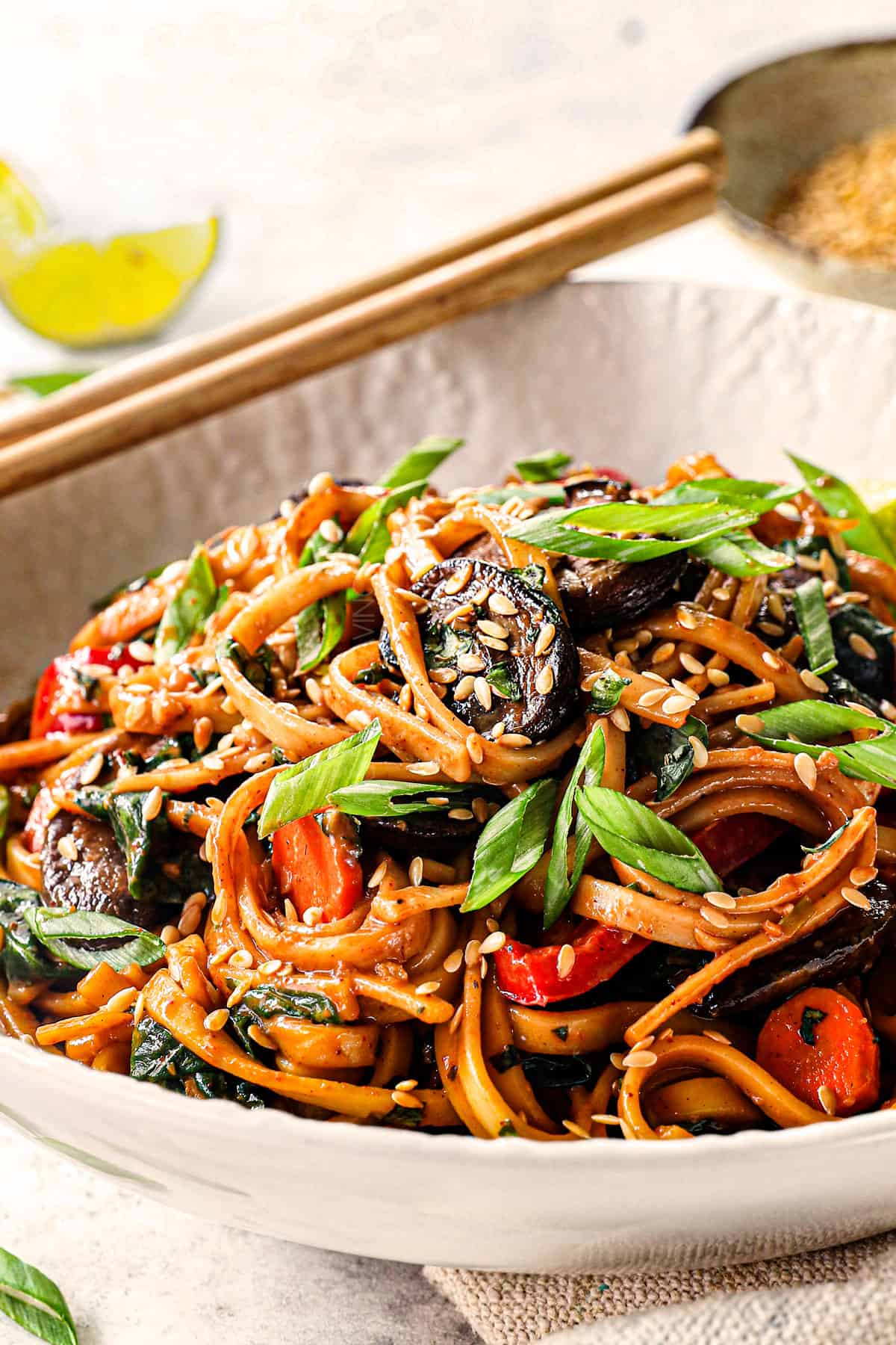up close of udon noodles stir fried with sauce in a bowl with vegetables
