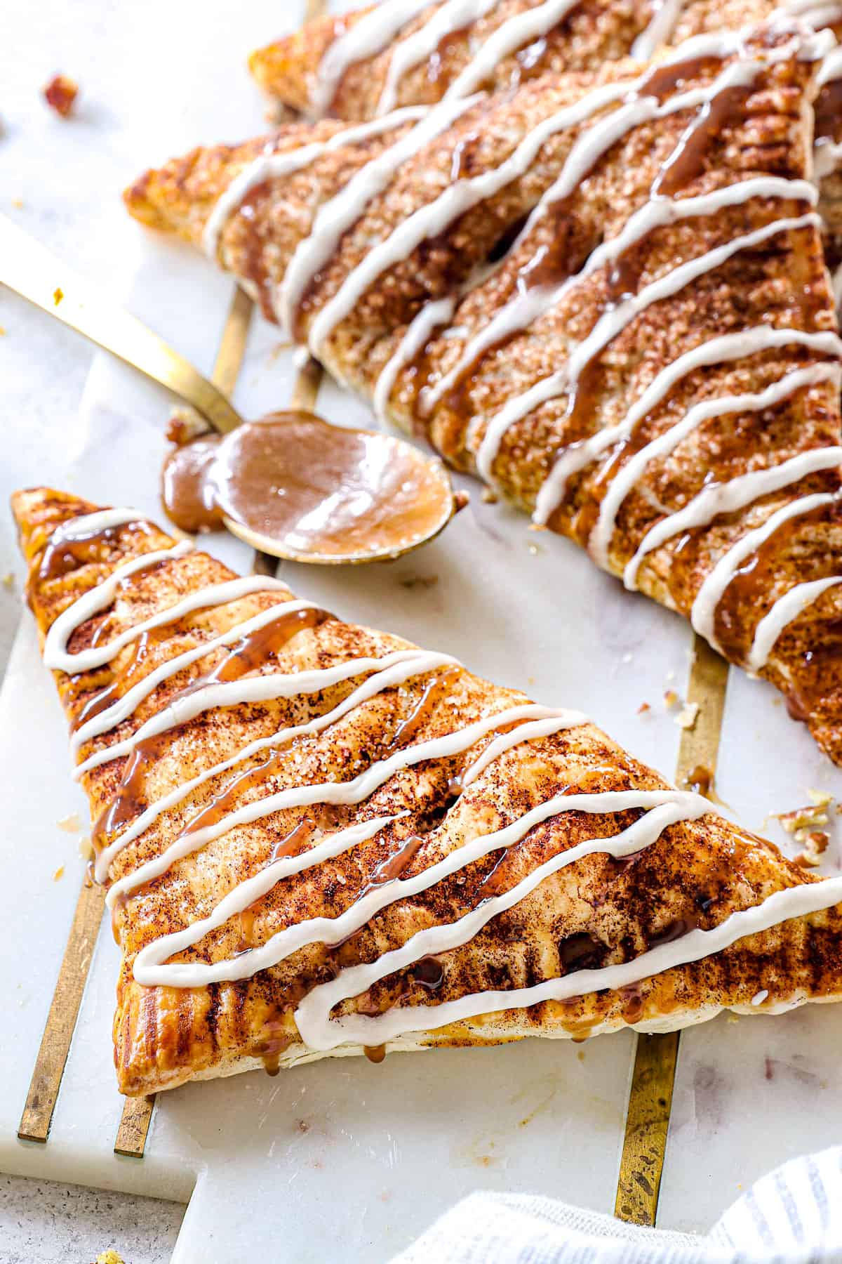 easy apple turnover made from puff pastry on a serving platter drizzled with glaze showing how to serve the dessert