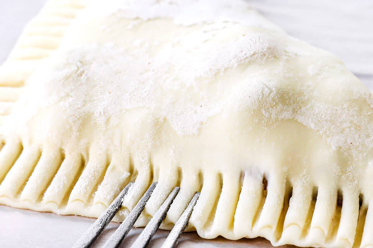 showing how to make apple turnover recipe by folding the puff pastry squares over the apples and crimping with a fork