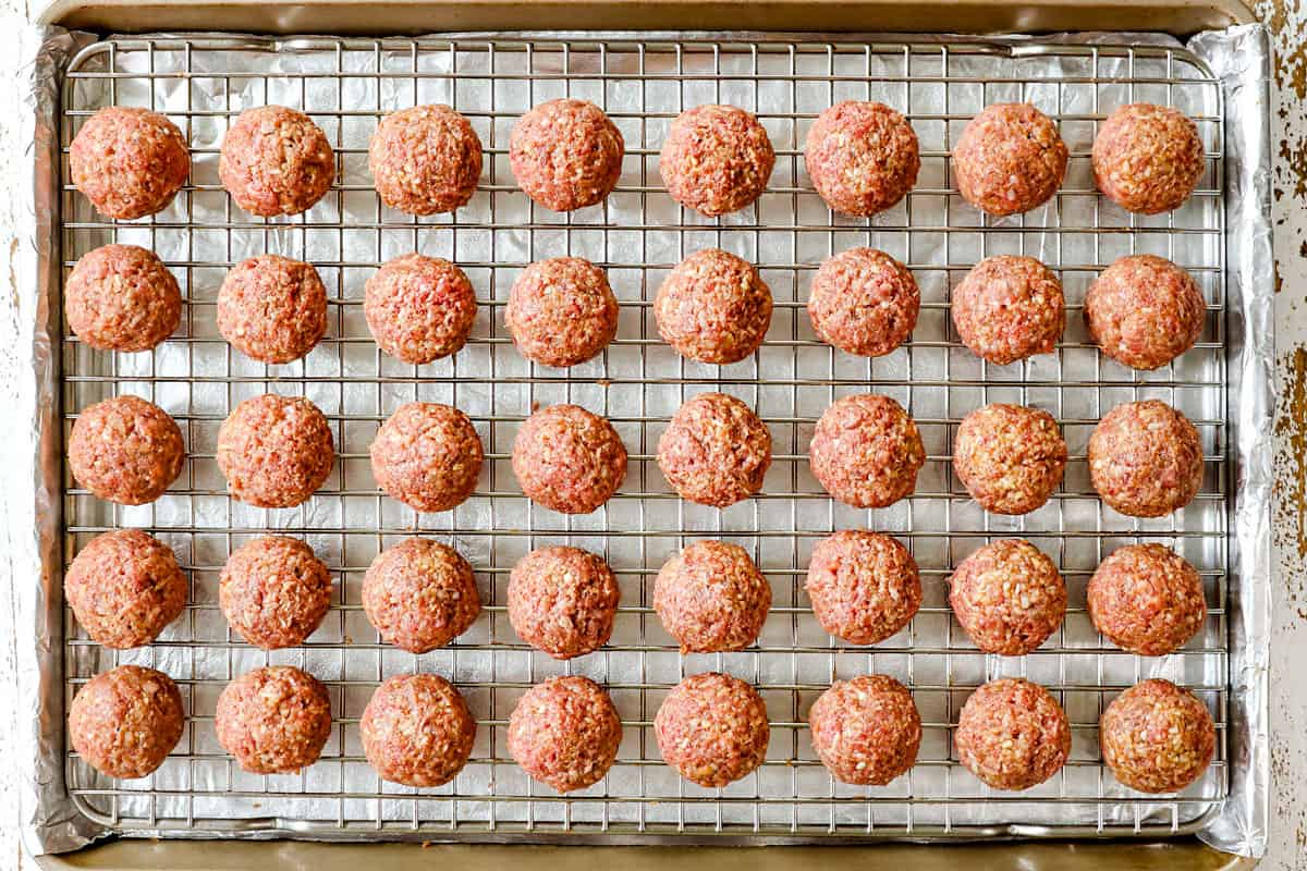 showing how to make grape jelly meatball recipe in the crockpot by rolling meatballs and adding them to an oven baking rack in order to sear in the oven