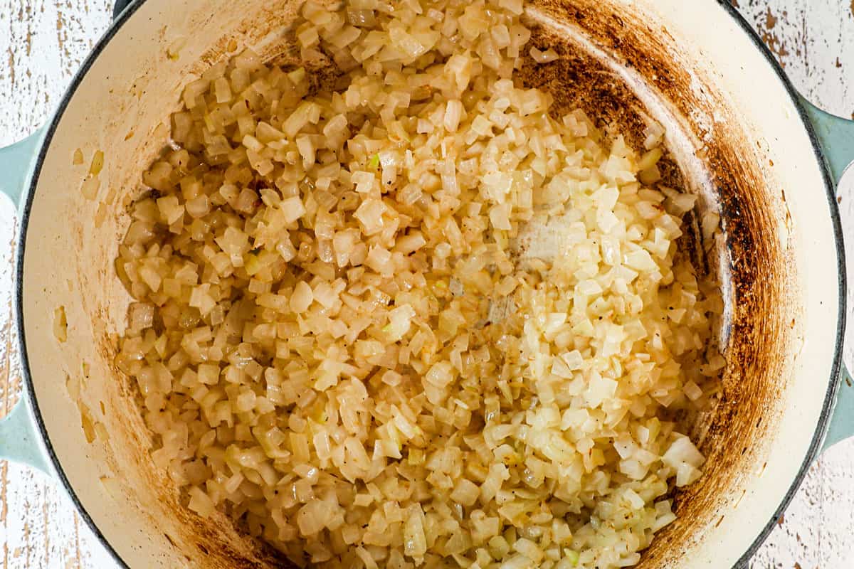 showing how to make mole sauce (Mole Poblano) by sautéing garlic and onions in a Dutch oven