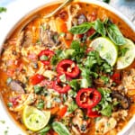 top view of coconut curry soup with chicken in a bowl with cilantro and limes