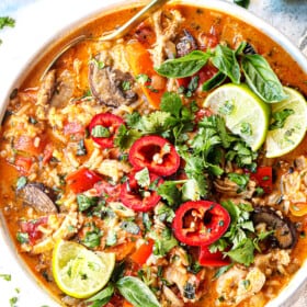 top view of coconut curry soup with chicken in a bowl with cilantro and limes