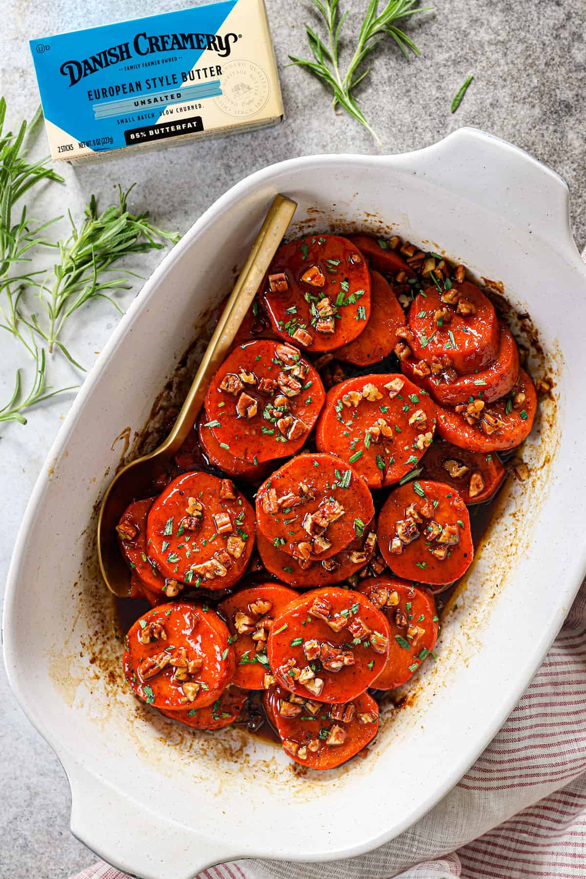 top view of candied yams (candied sweet potatoes) in a serving dish garnished with rosemary