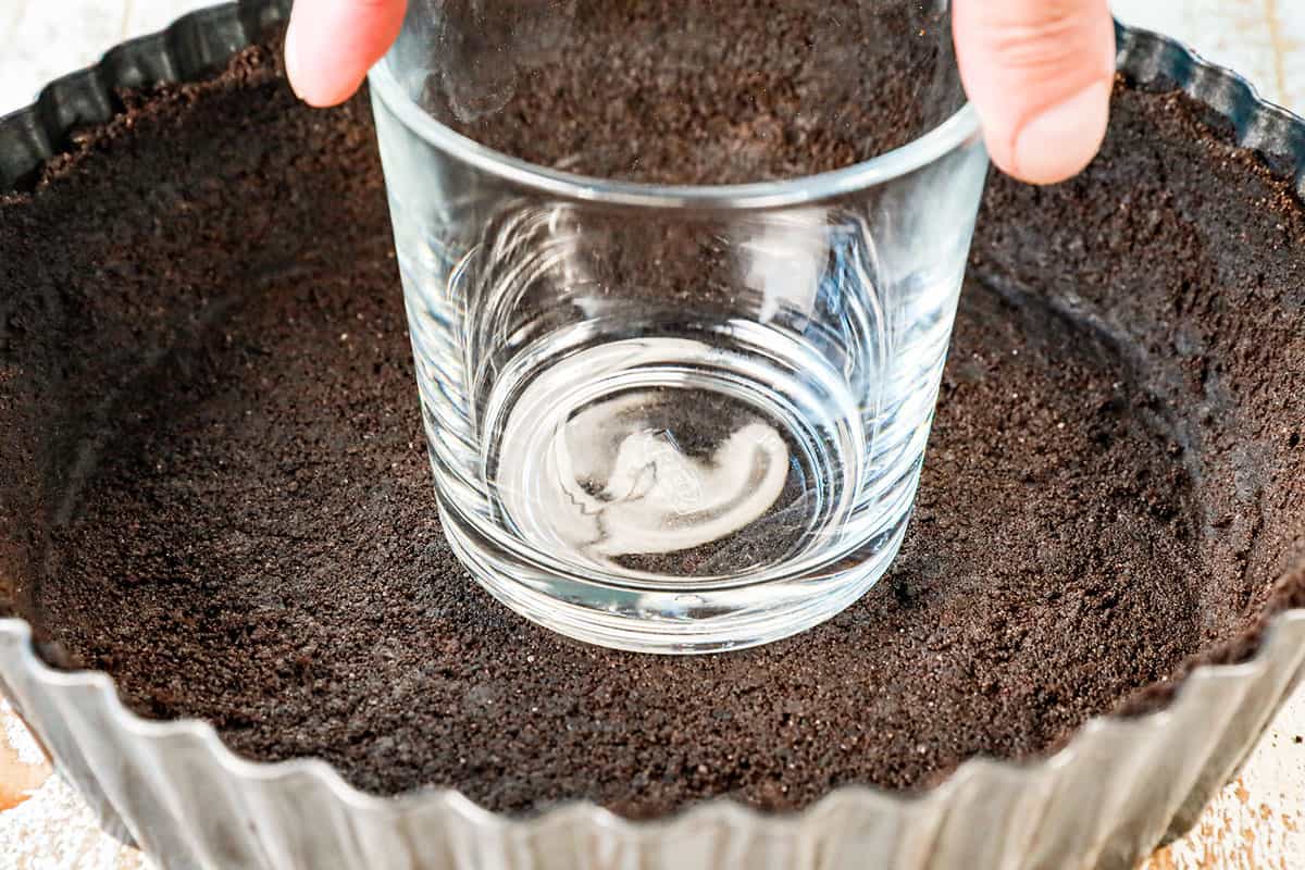 showing how to make chocolate cream pie by pressing Oreo crust into the bottom of a pie pan