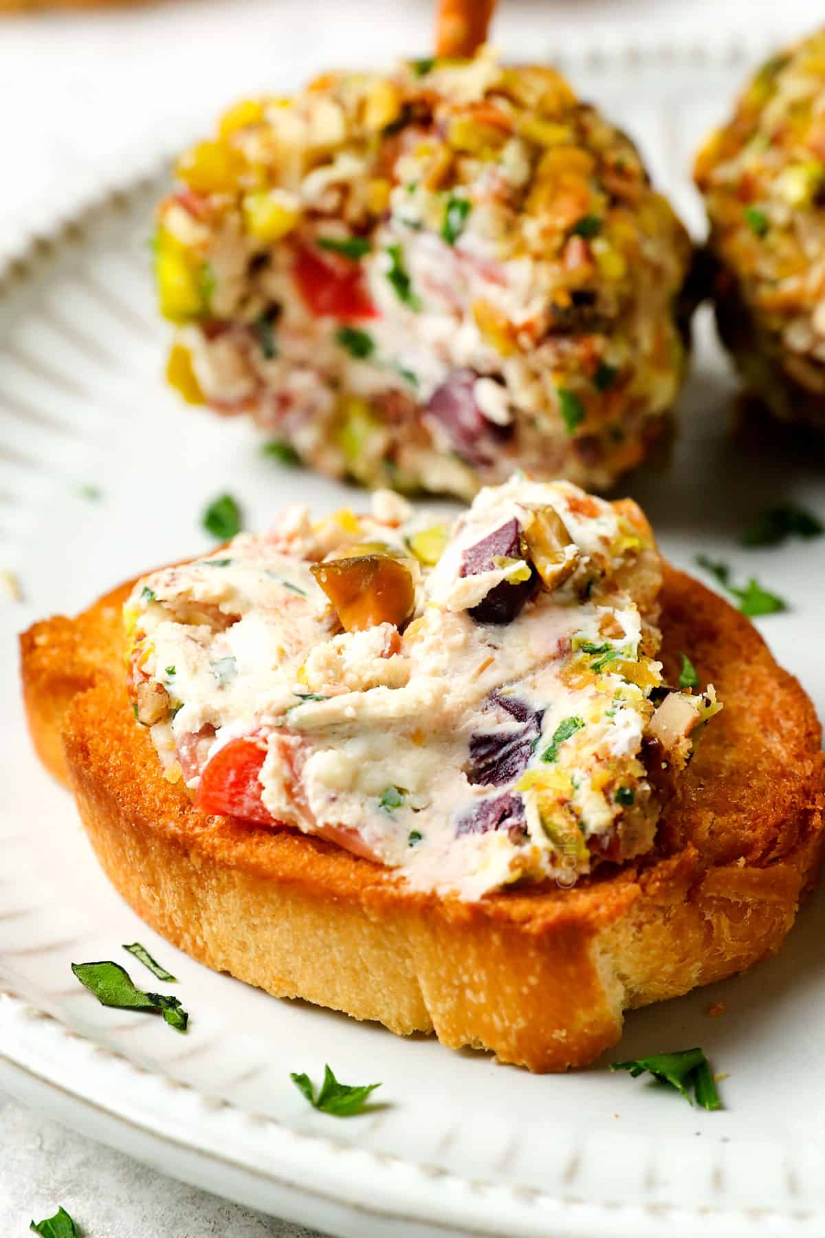 showing how to serve mini cheese balls by spreading on crostini