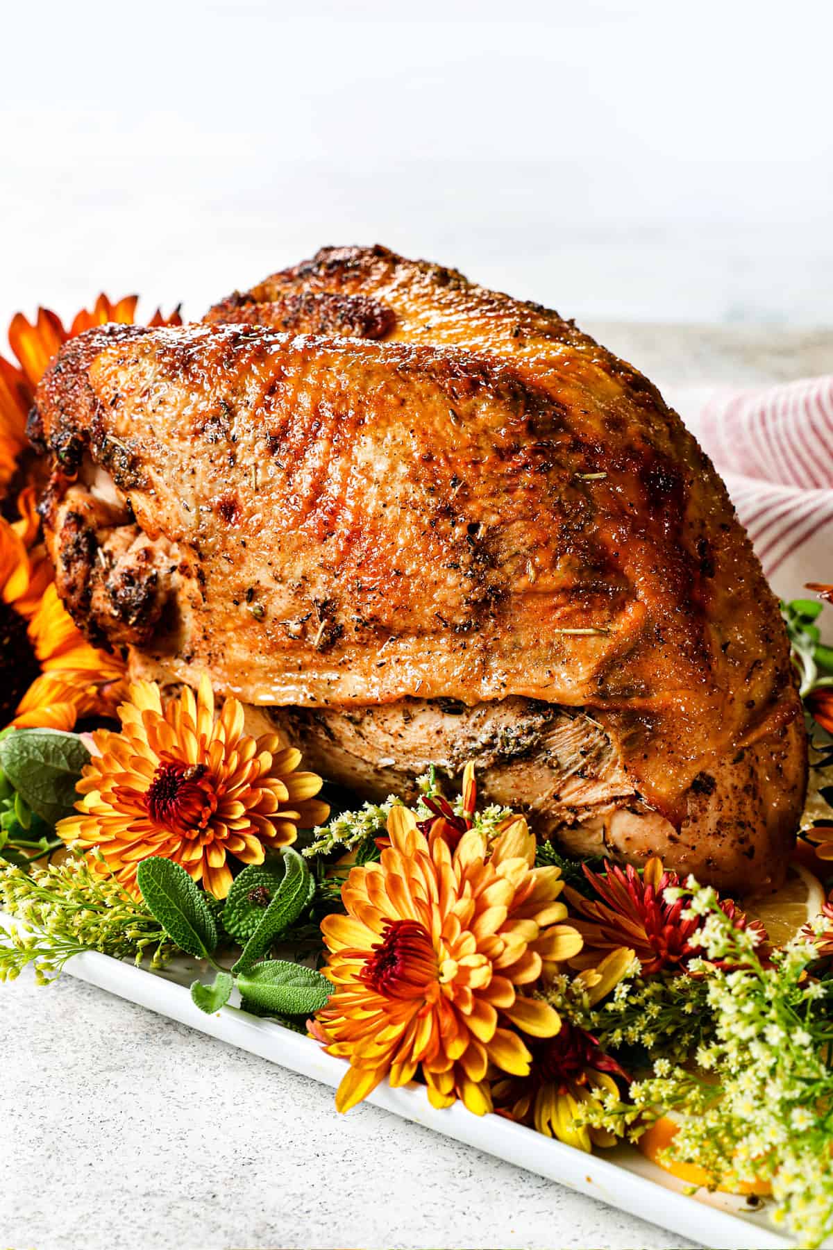 showing how to serve roast turkey breast by placing on a platter surrounded by flowers
