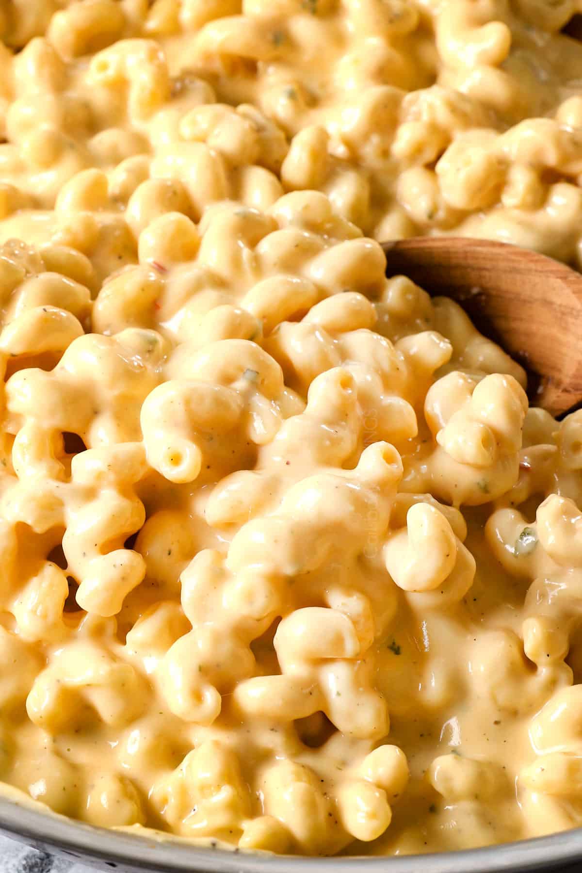 showing how to make baked macaroni and cheese recipe by stirring the pasta and sauce together