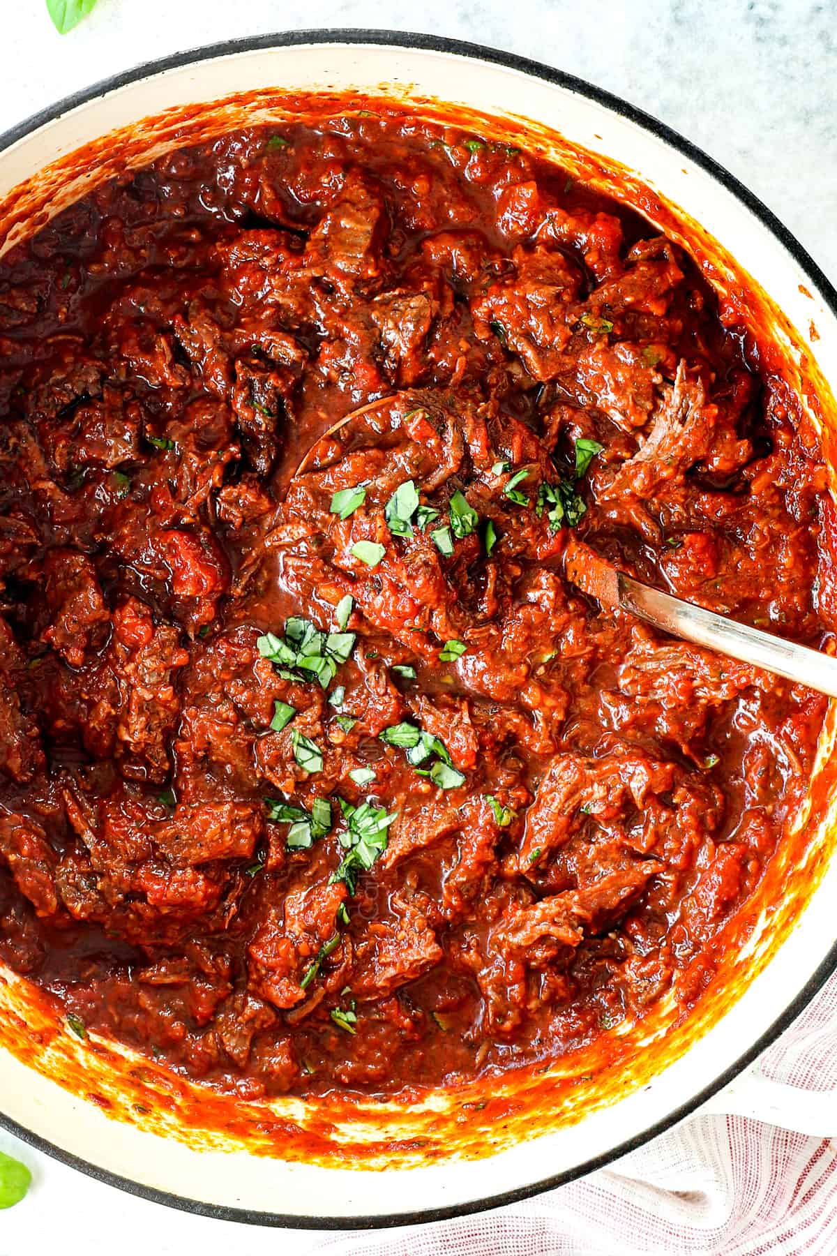 up close of twirling beef ragu recipe on a fork showing the saucy ragu sauce