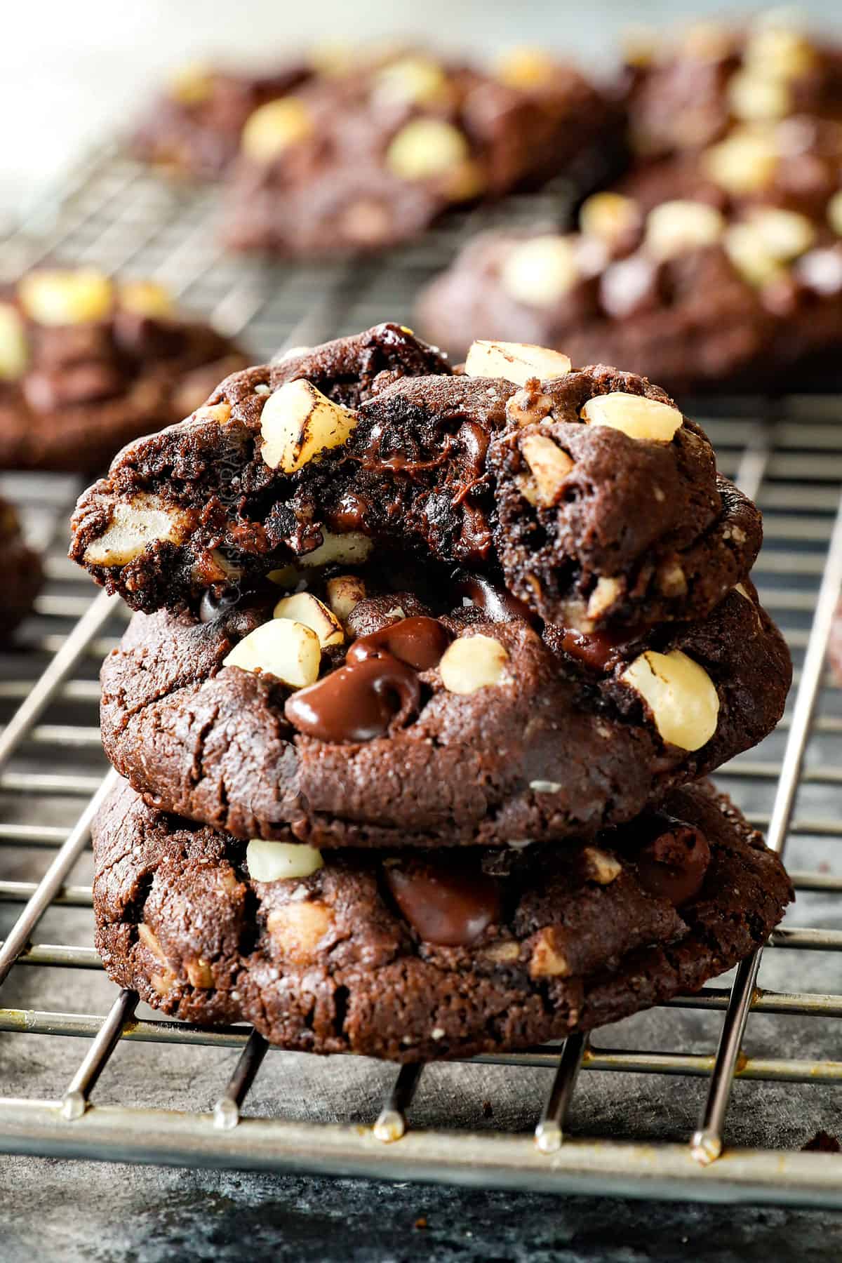 macadamia nut cookies with a bite taken out of a cookie showing the macadamia nuts and melted chocolate inside
