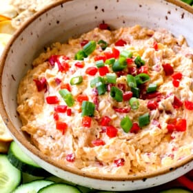 showing how to serve pimento cheese recipe adding to a platter with cucumbers, celery, bell peppers, cauliflower and crackers
