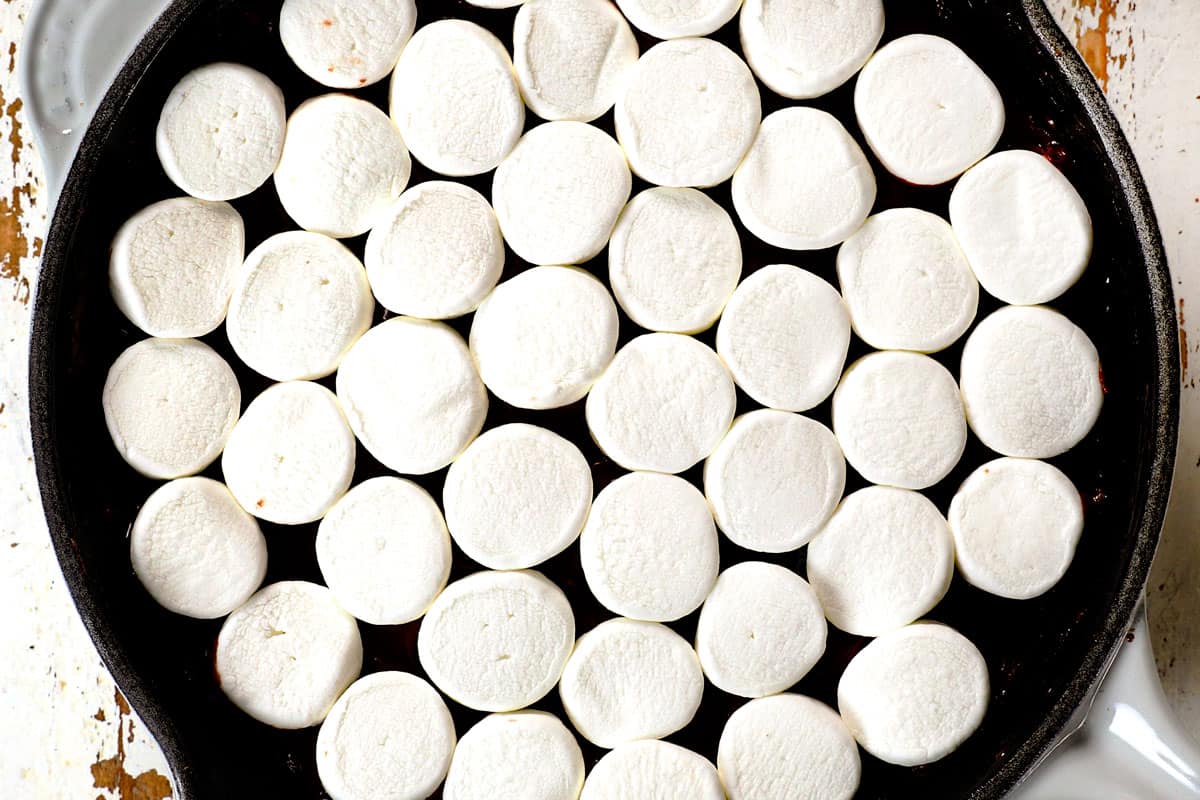 showing how to make s'mores dip by adding marshmallows on top of dip