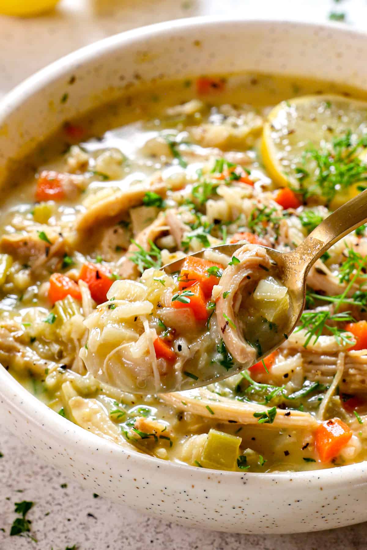 up close of a spoonful of Avgolemono Soup recipe (Greek Lemon Chicken Soup) showing how silky the broth is