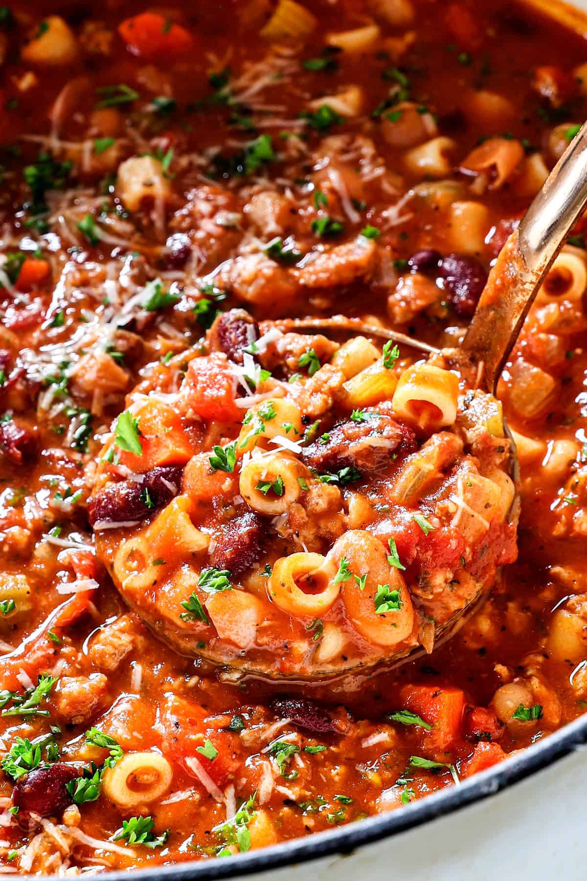 up close of a ladle serving pasta e fagioli soup showing how thick it is
