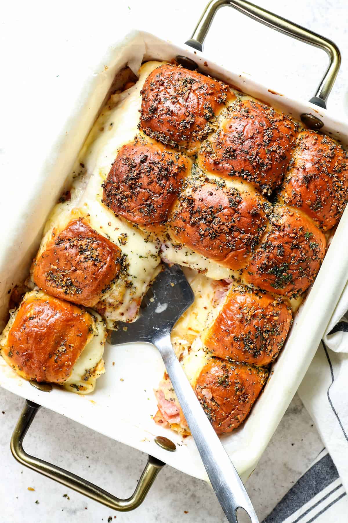top view of baked Hawaiian ham and cheese sliders in a 9x13 dish showing cutting into pieces