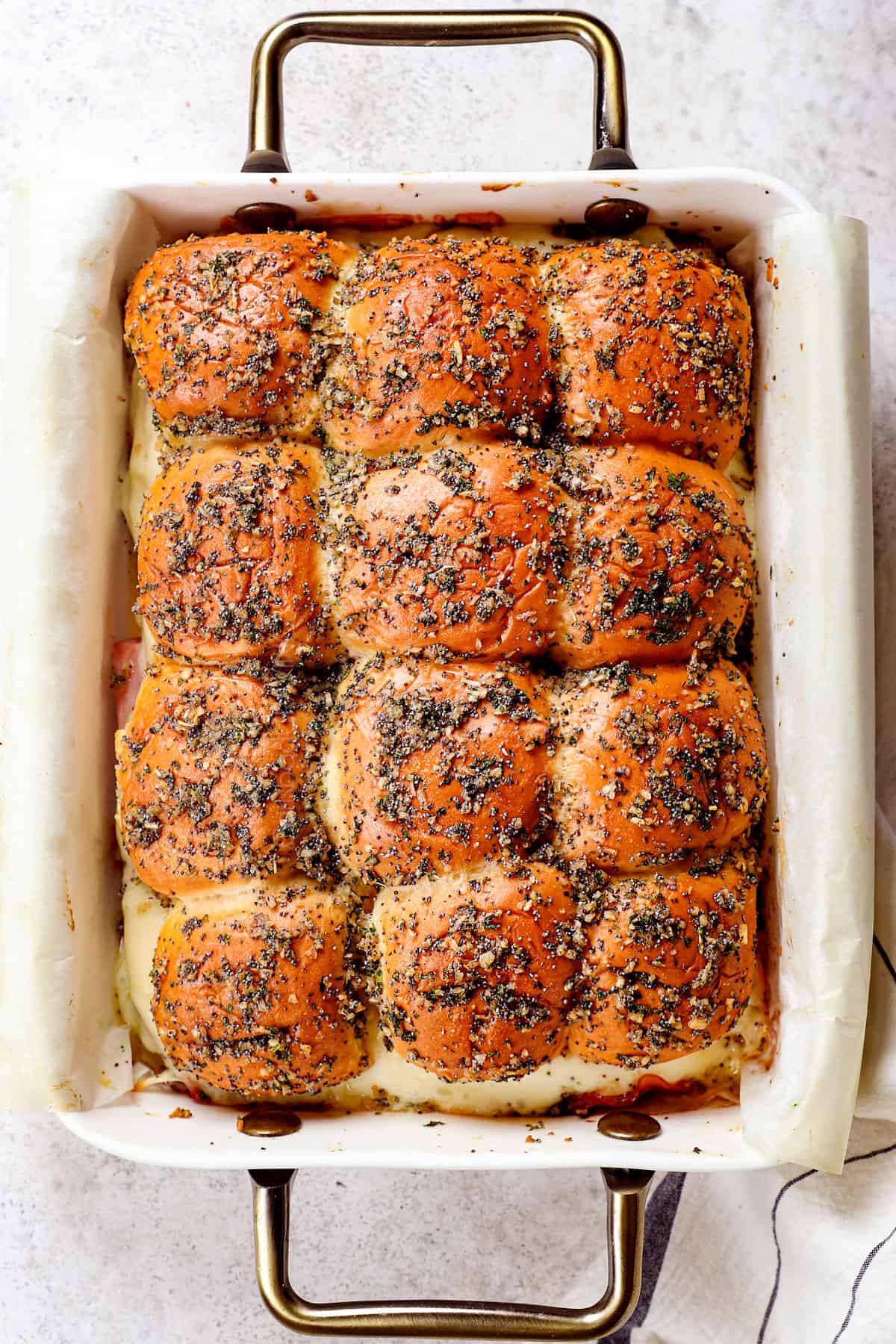 showing how to make ham and cheese sliders recipe by baking in the oven until the cheese is melted and the tops of the Hawaiian rolls are golden