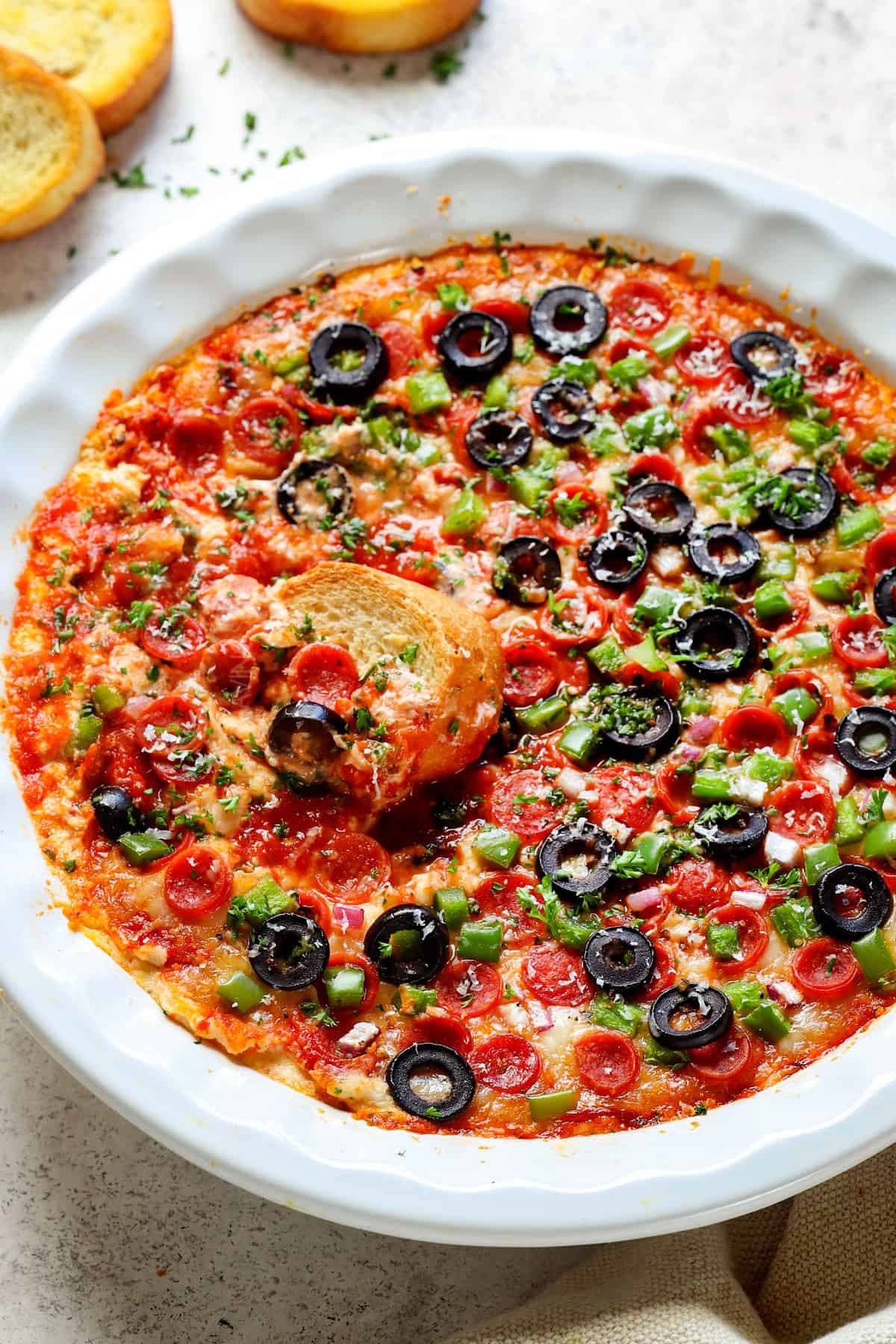 show how to make pizza dip by adding pepperoni, bell peppers, olives and red onions