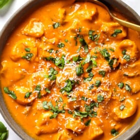 top view of a bowl of tortellini soup recipe showing how to serve with basil and Parmesan