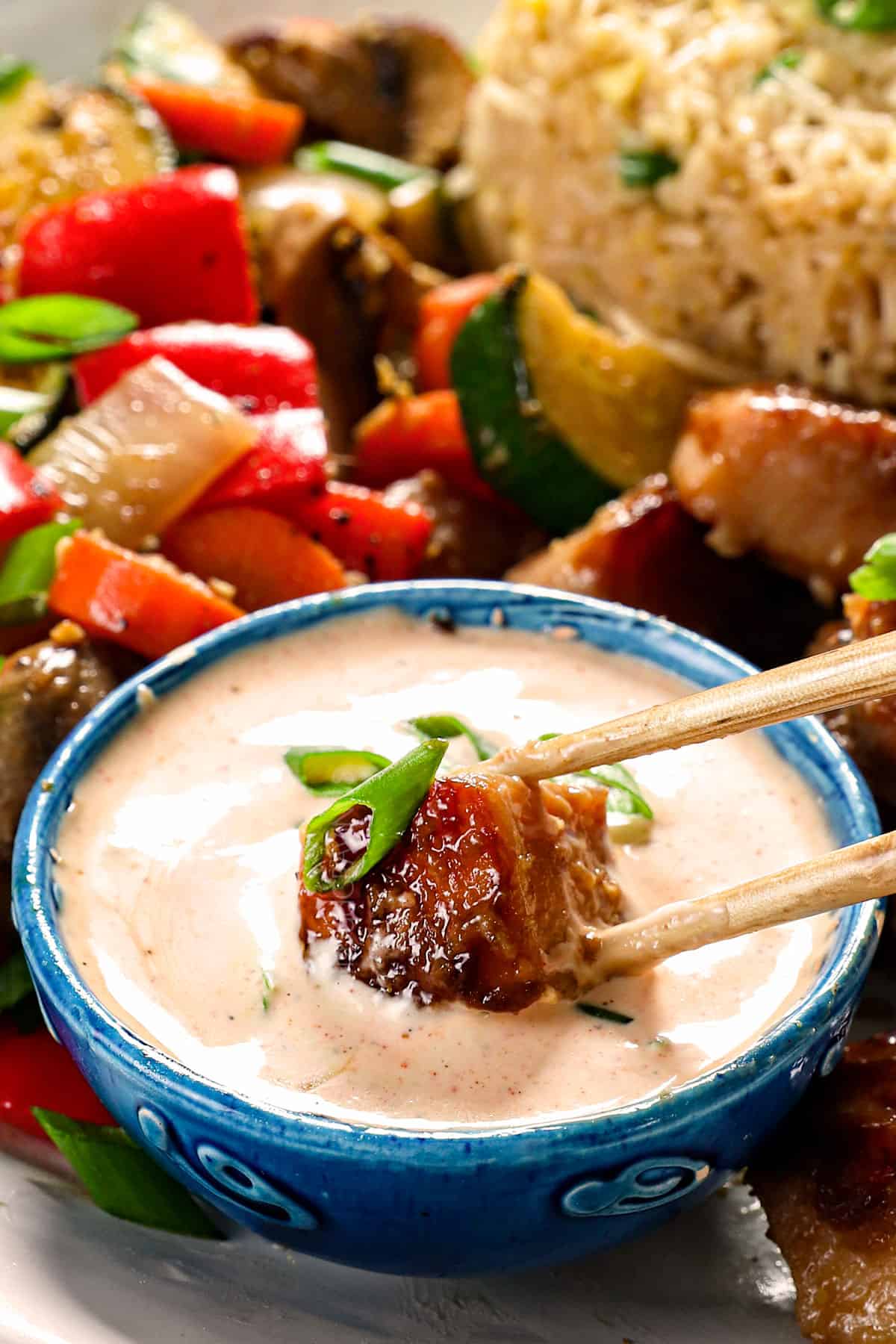 showing how to serve homemade Yum Yum Sauce recipe by dipping hibachi chicken in the sauce