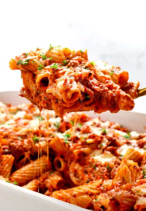 up closer of baked rigatoni with a cheese pull from serving from the casserole dish