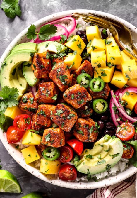top view of chicken bites being served in a bowl with rice and avocados