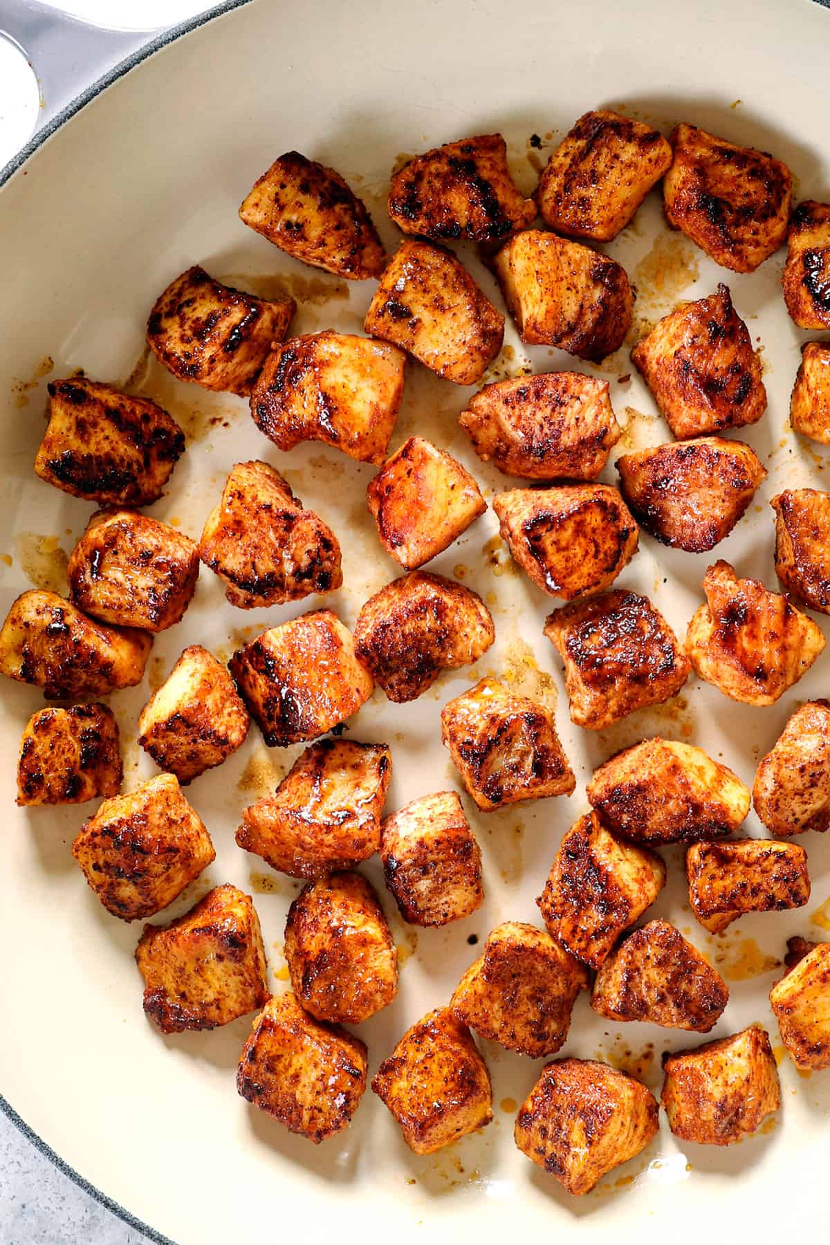 showing how to make chicken bites by searing the cubed chicken in a pan