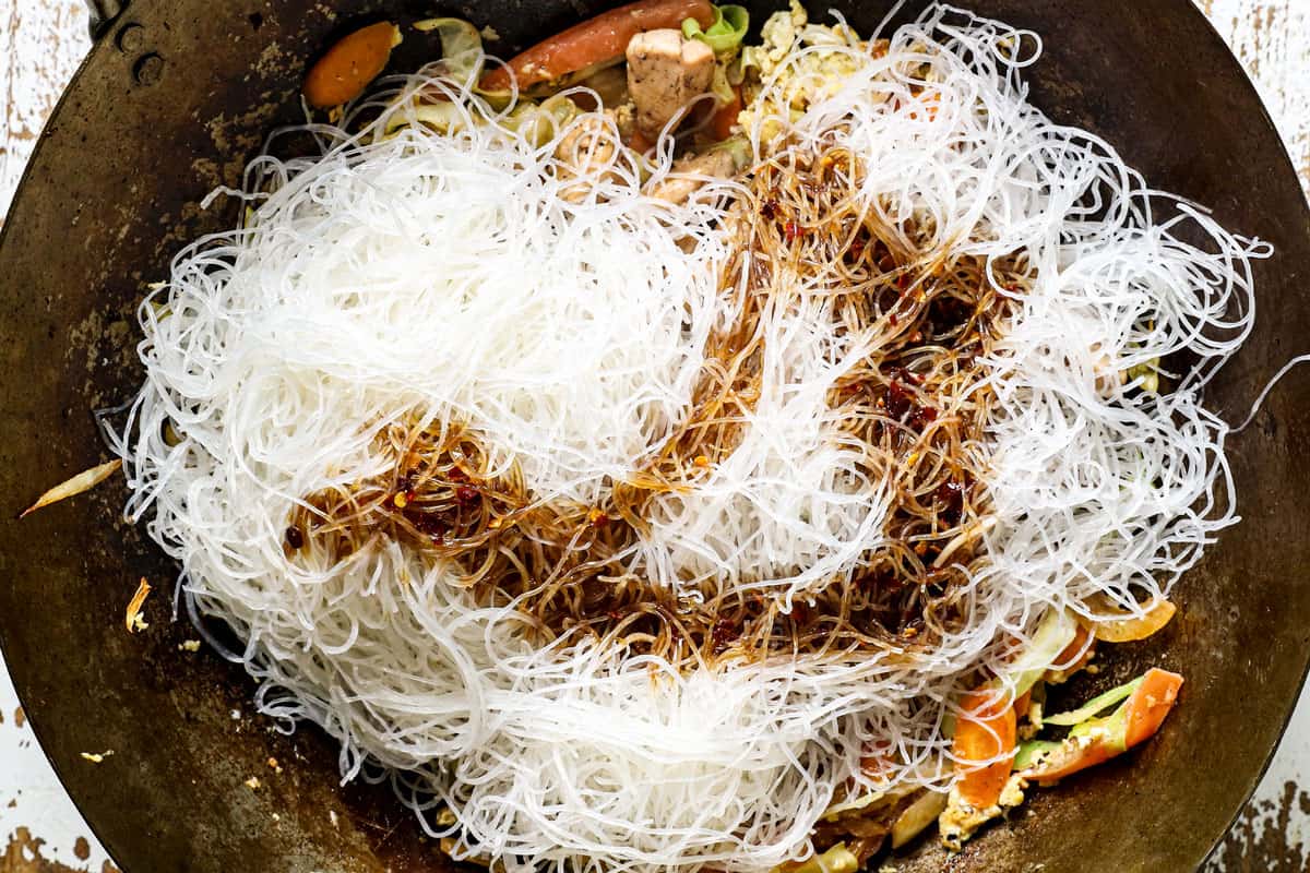 showing how to make Thai Pad Woon Sen recipe by adding the stir fry sauce and glass noodles and stirring everything together