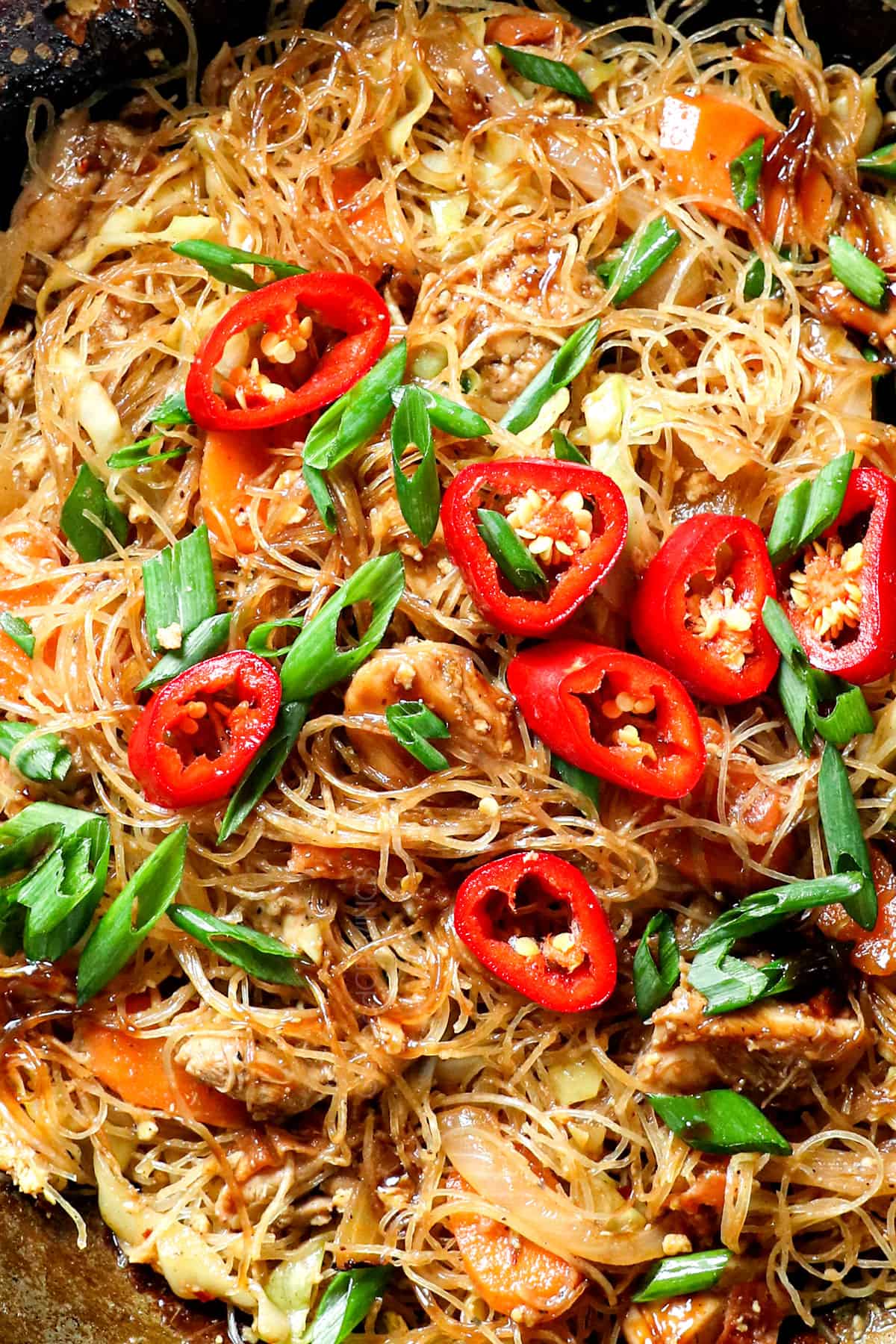 showing how to make pad woon sen by stirring the glass noodles with the sauce in a wok