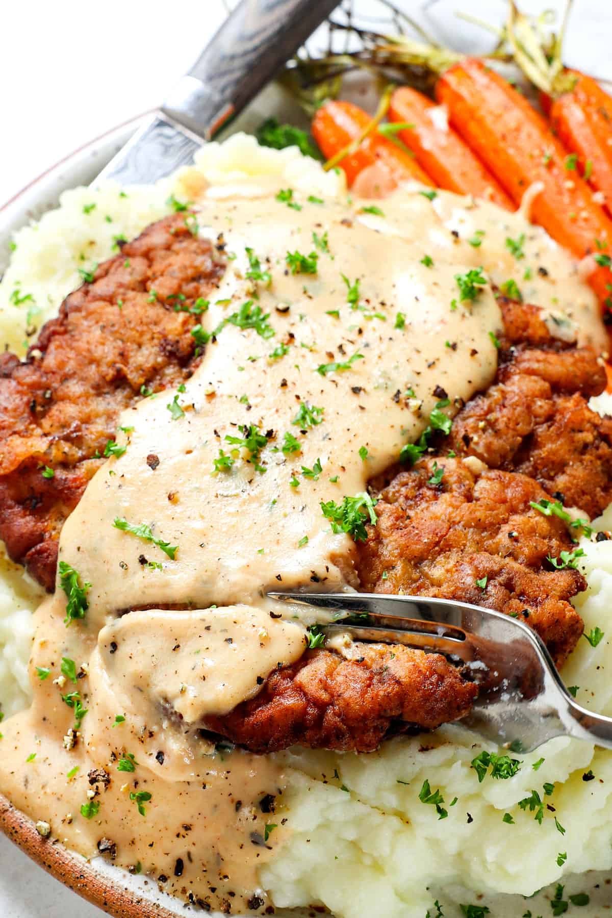 taken a bite of chicken fried steak (country fried steak( showing how crispy it is