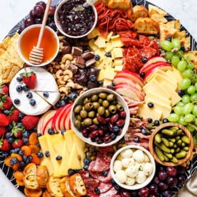 showing how to make a charcuterie board by adding crackers and bread/crostini to the board