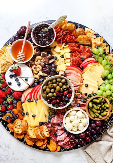 showing how to make a charcuterie board by adding crackers and bread/crostini to the board