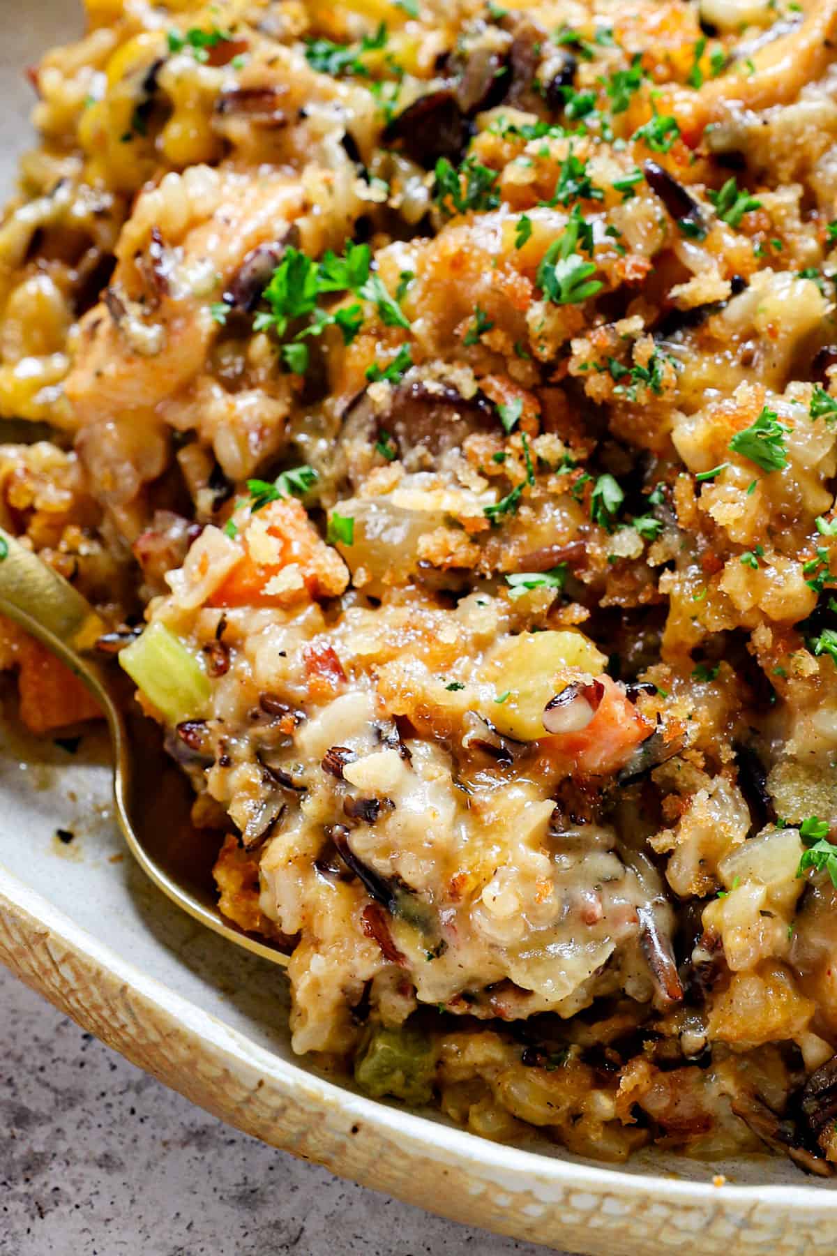 showing how creamy chicken wild rice casserole is with an up close of a spoon taking a bite