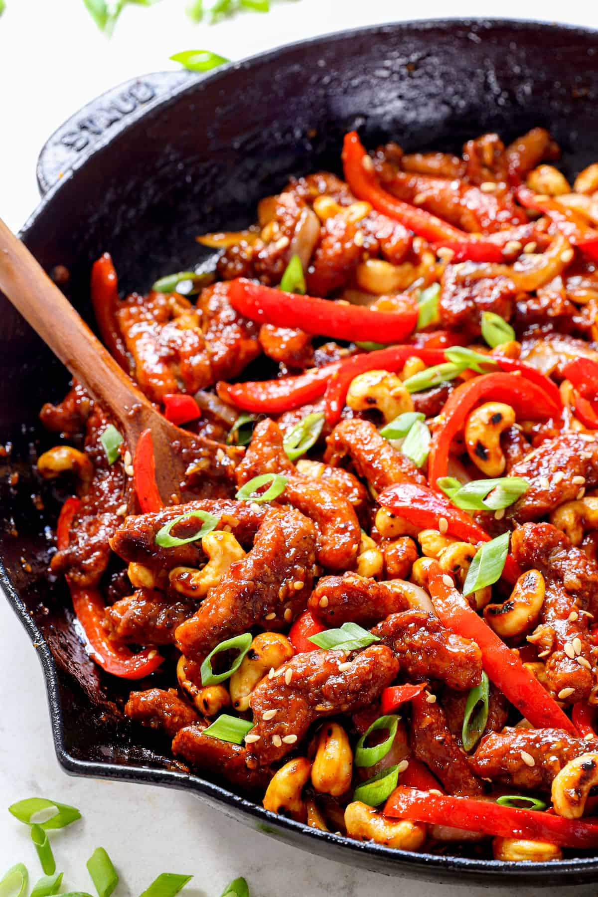 showing how to make Dragon chicken by stirring chicken, cashews, bell peppers together in a skillet
