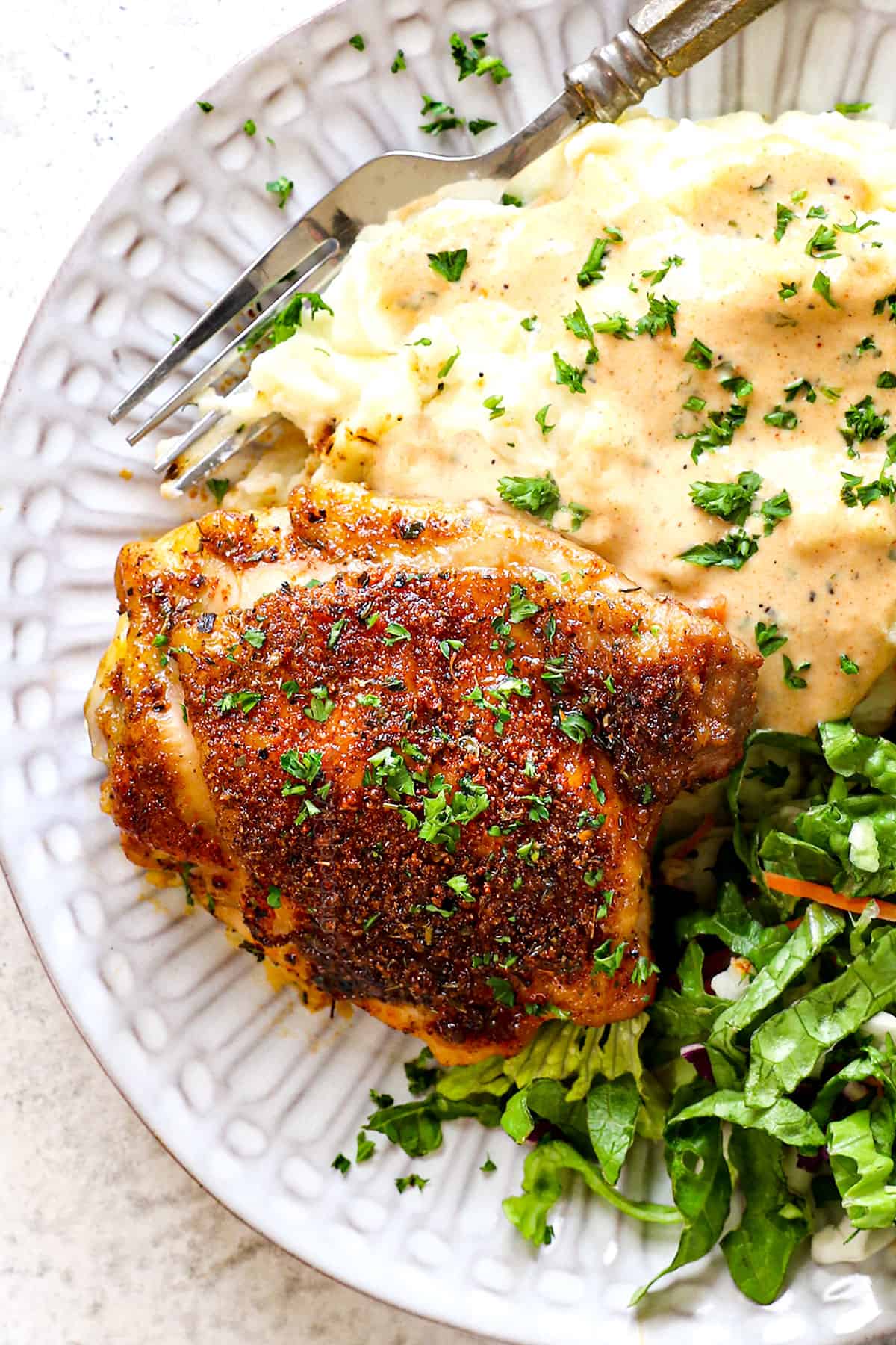 top view of serving baked chicken thighs bone in on a plate with mashed potatoes and salad