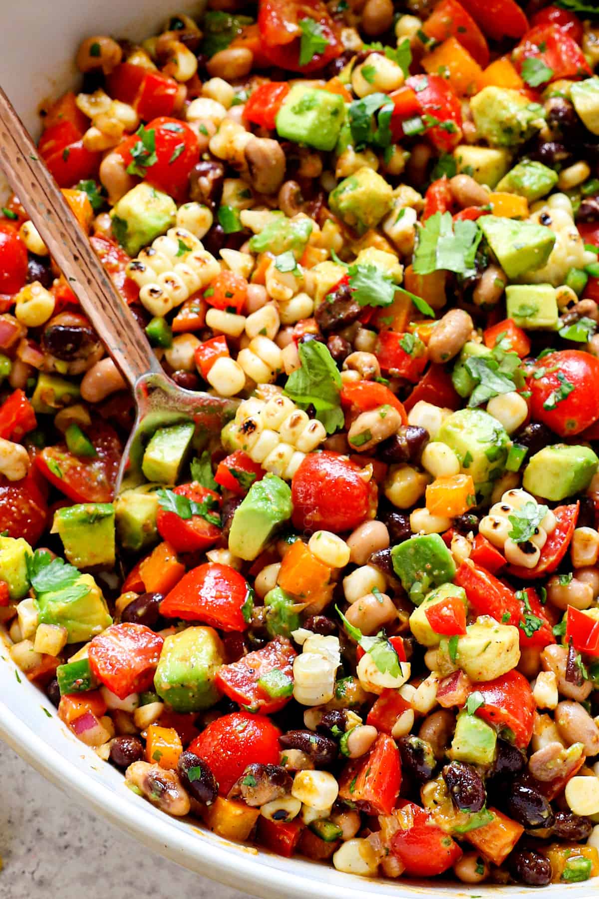 Texas Caviar being served in a bowl with a spoon garnished by cilantro