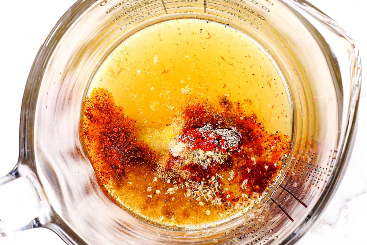 showing how to make cowboy caviar (Texas Caviar) recipe easy by adding olive oil, lime juice, vinegar, chili powder, cumin and salt to a bowl to make the dressing