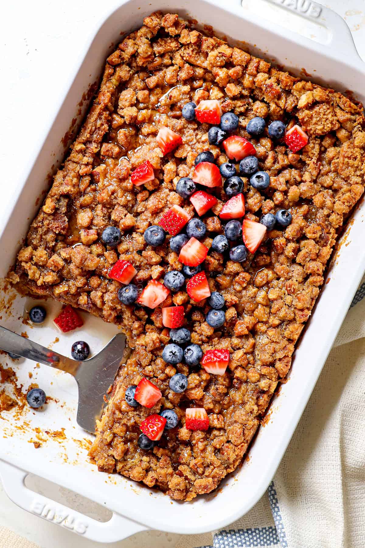 showing how to serve French Toast Bake (French Toast Casserole) by topping it with strawberries and blueberries
