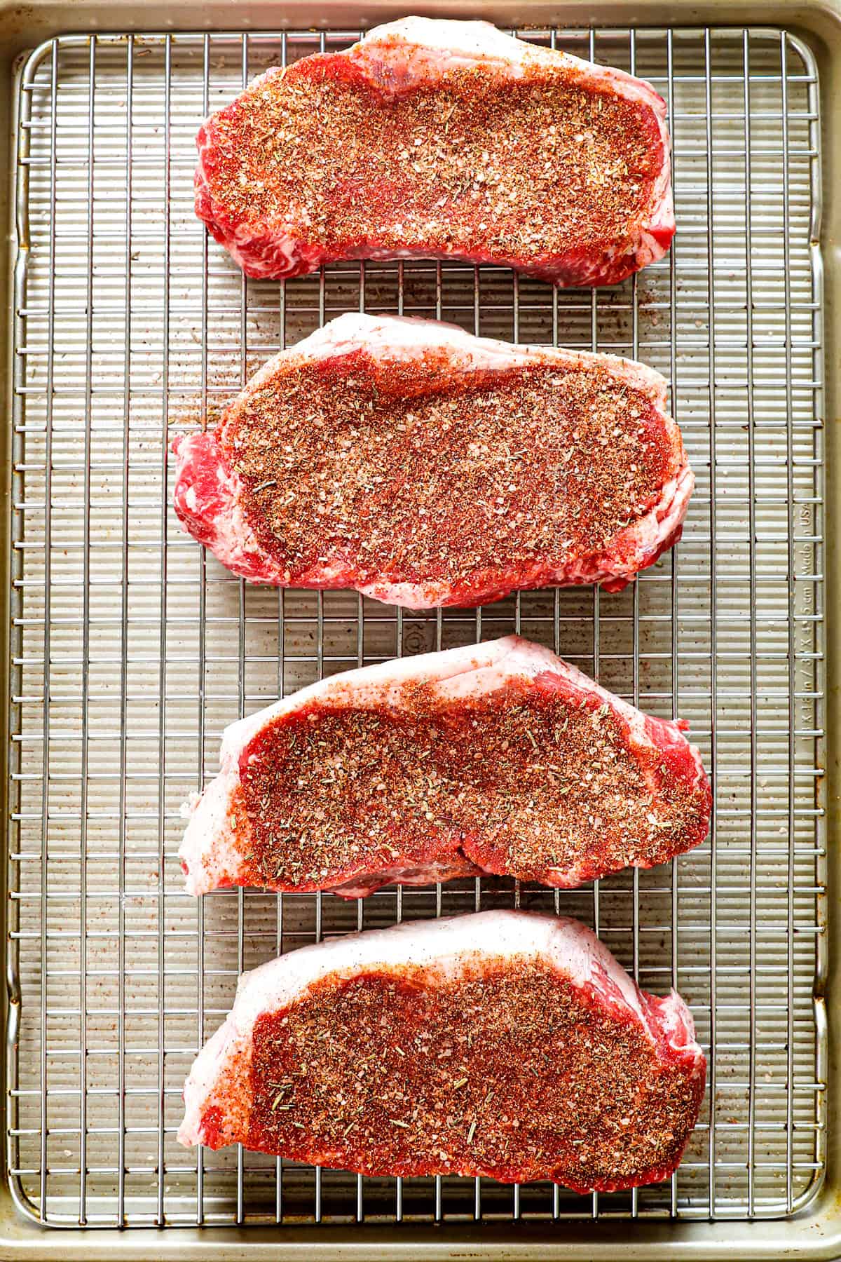 top view showing how to season steaks with steak rub on a wire rack